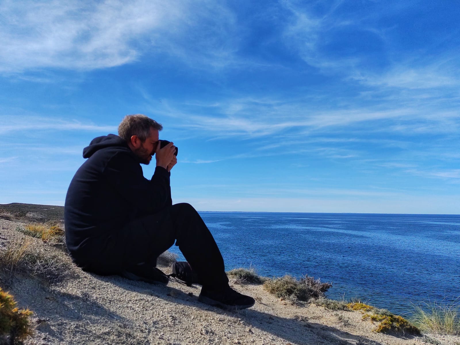 Nelson E. Bolivar taking a photograph by the coast